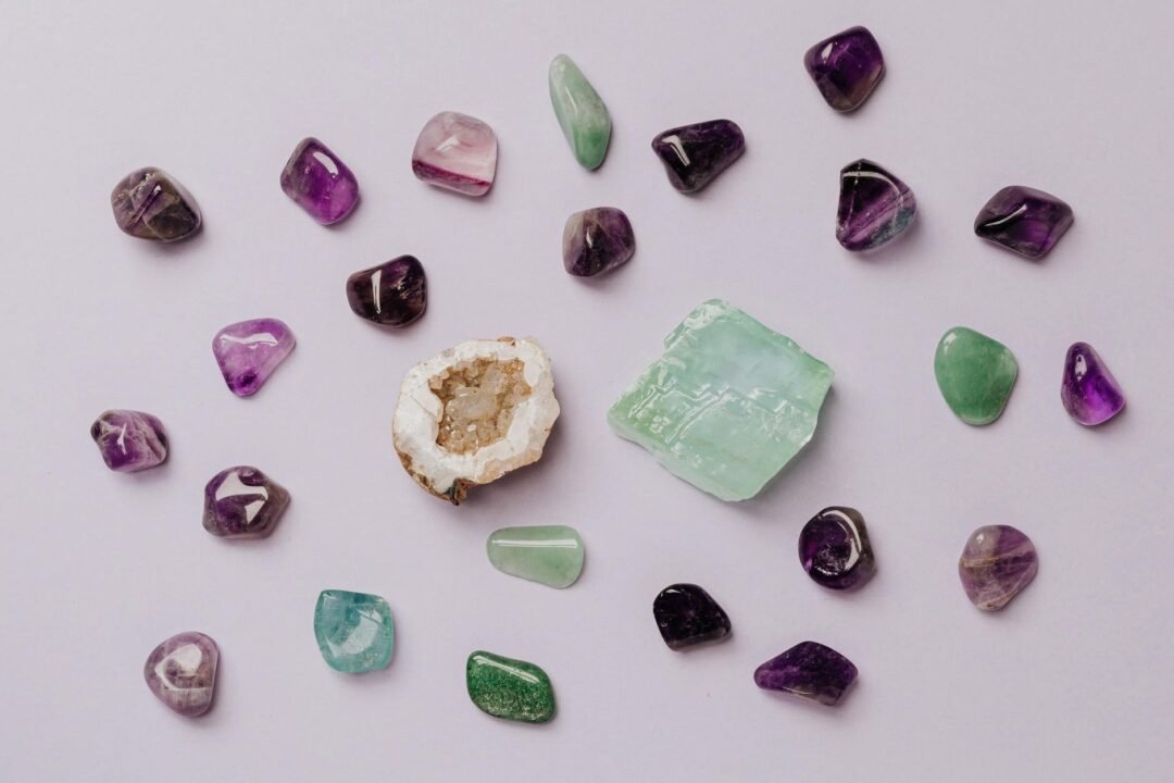Flat lay of assorted polished gemstones including amethyst and jade on a light background.